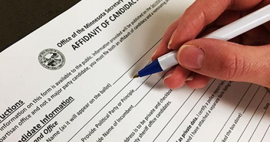 Hand filling out an affidavit of candidacy form. 