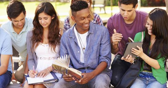 A group of teens holding textbooks and chatting