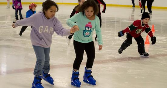 Children ice skating at an arena.