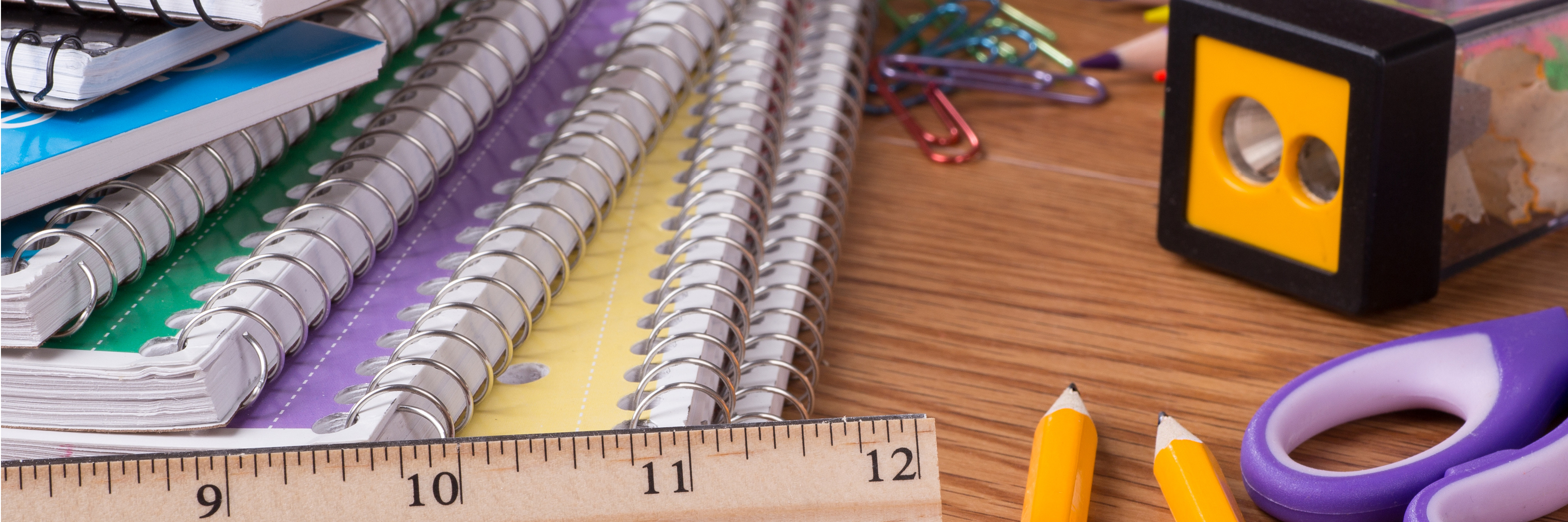 Various school supplies, including notebooks, pencils and ruler, on top of a wooden table